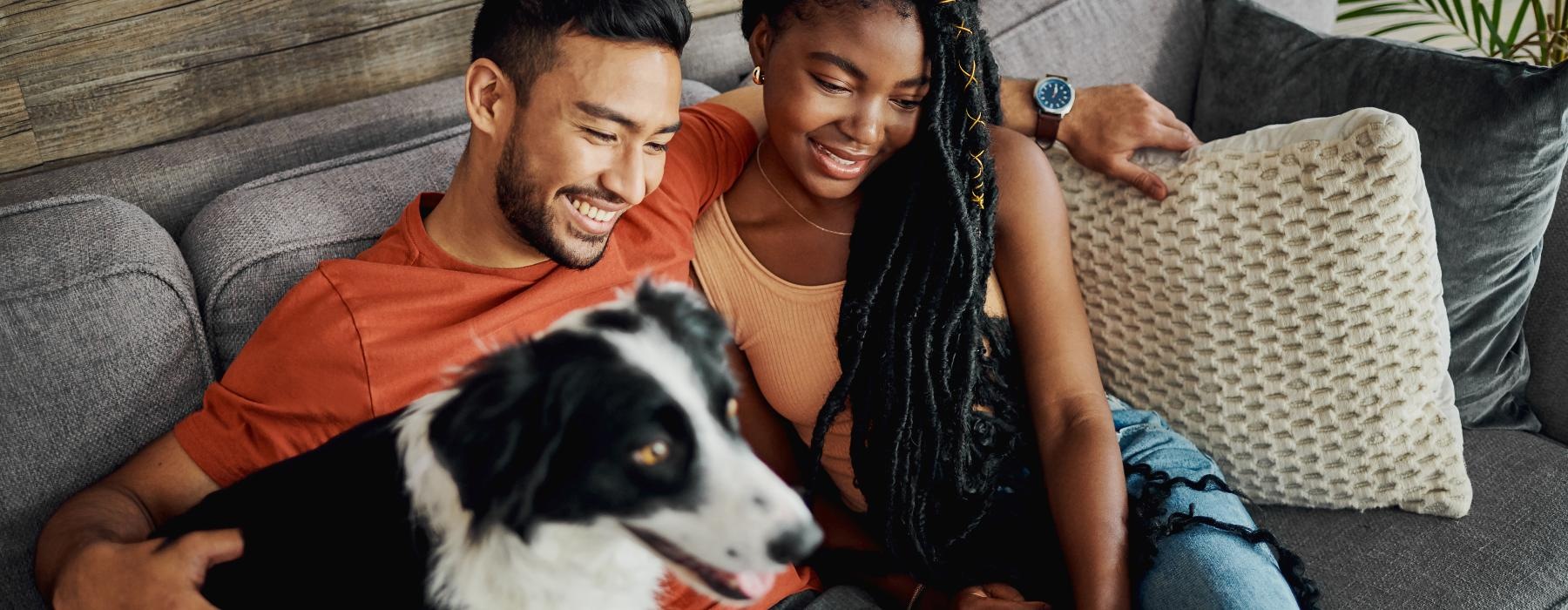 a man and woman sitting on a couch with a dog