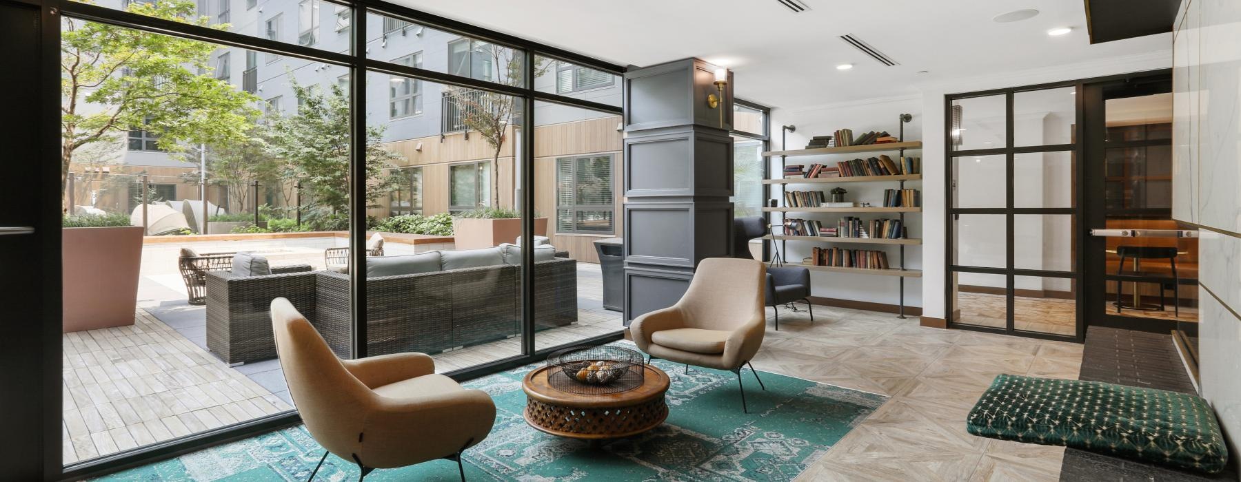 a room with a glass wall and a table with chairs and a bookcase with a bookcase