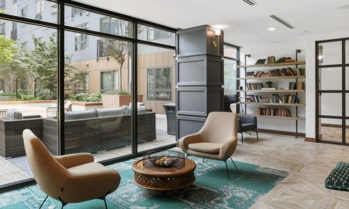 a room with a glass wall and a table with chairs and a bookcase with a bookcase